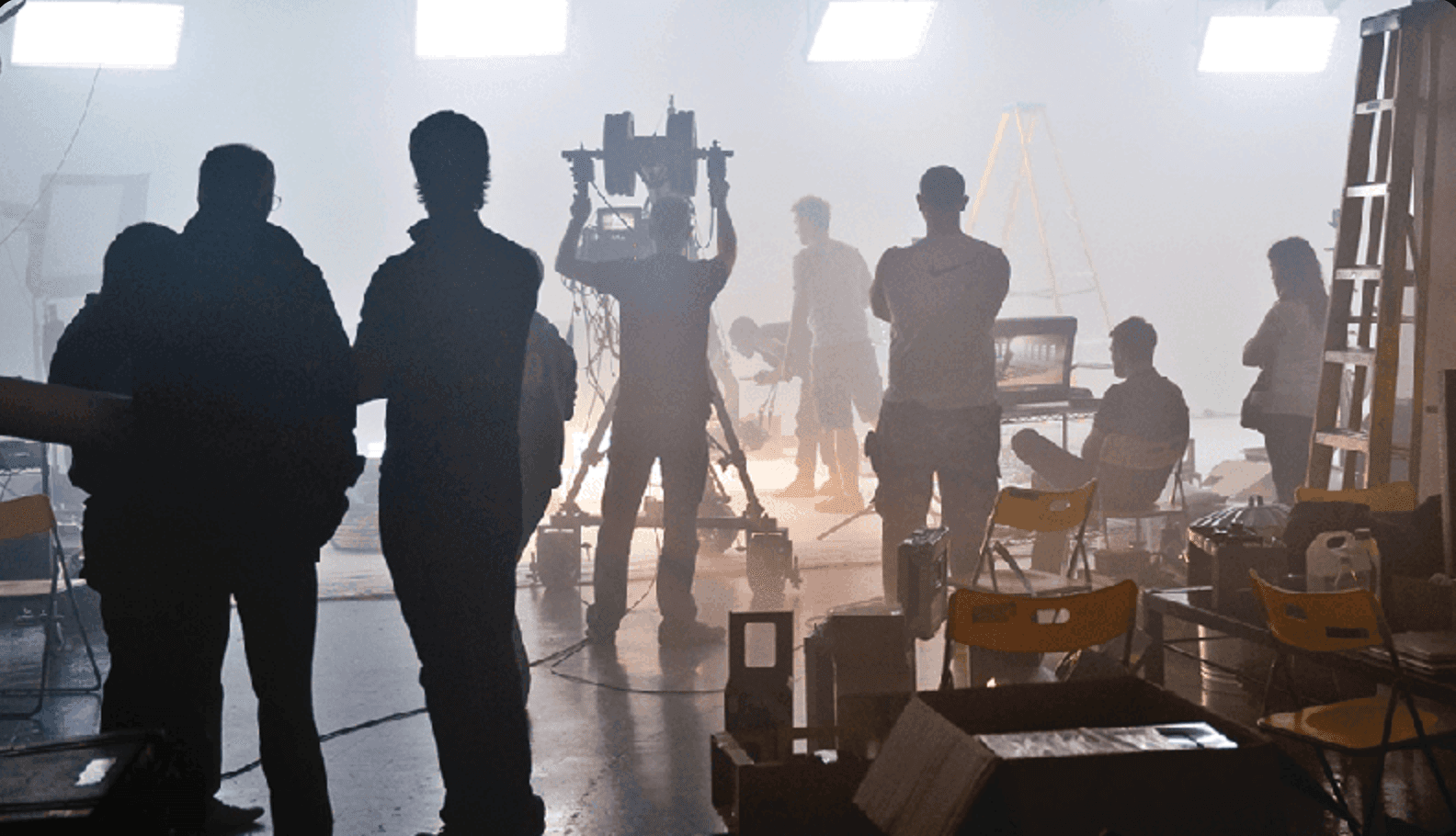 A camera operator filming a person speaking on a set