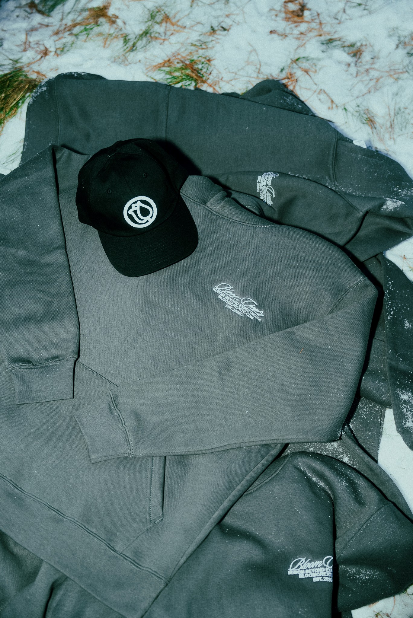 The black Bloom hoodie and baseball cap on a wooden table