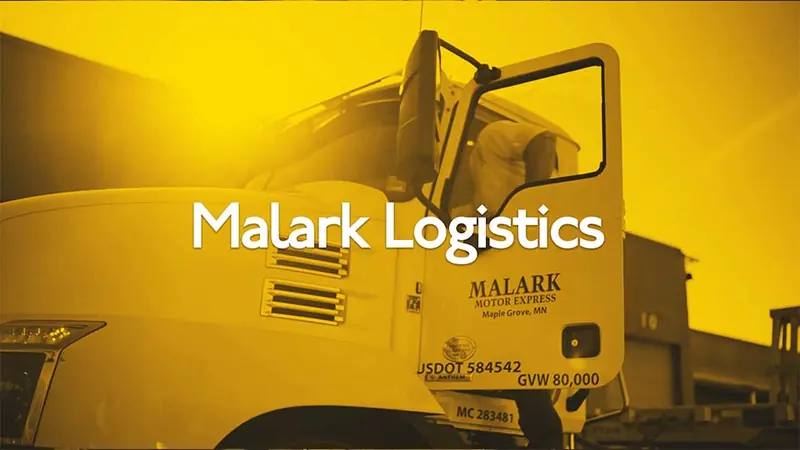 A person at a desk beside the Malark logo, from the Malark Logistics commercial